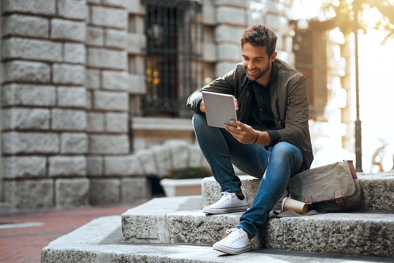 Tablet, smile and online with man in city for communication, social media and connection. Networking, newsletter and location app with person in urban downtown for search, digital or internet